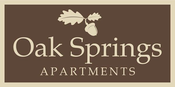 Oak Springs Apartments logo, beige on brown with a leafed acorn at the top