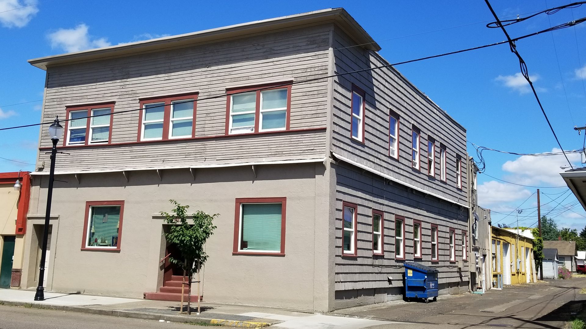Armory Apartments in downtown Albany Oregon – gray building exterior with tree alley and light post.