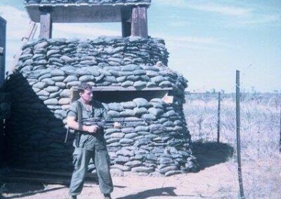 A man in a military uniform is standing in front of a pile of rocks.