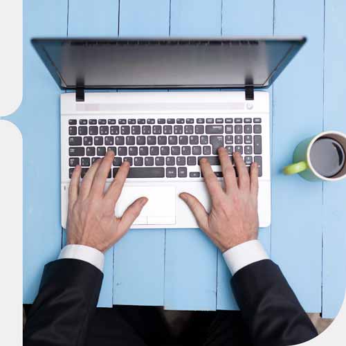 Working at an Apple Macbook computer from birds eye view on a blue picnic bench