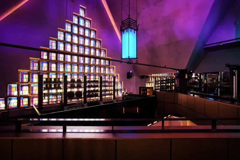 Piramide van schermen in een paars verlichte bar, met een hoge blauwe lantaarn en een trap.