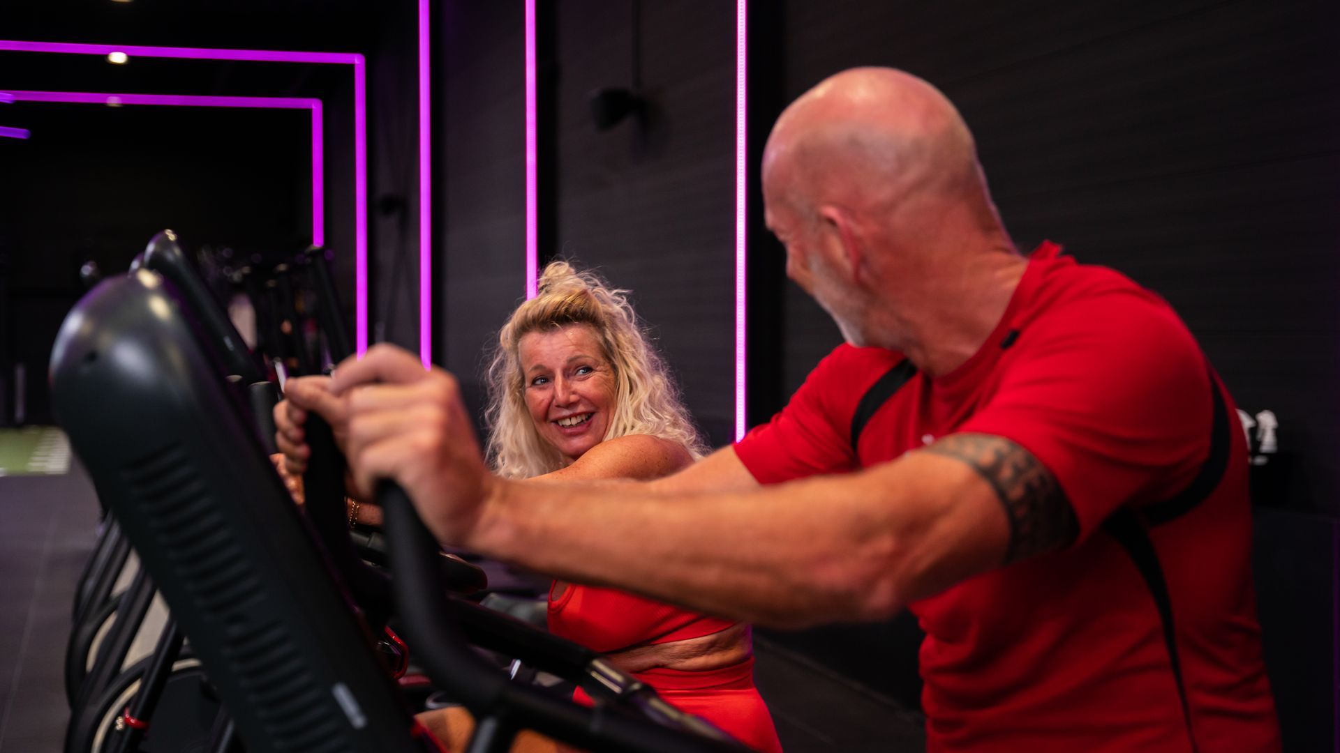 Vrouw op fitnessapparaat met trainer in sportschool.