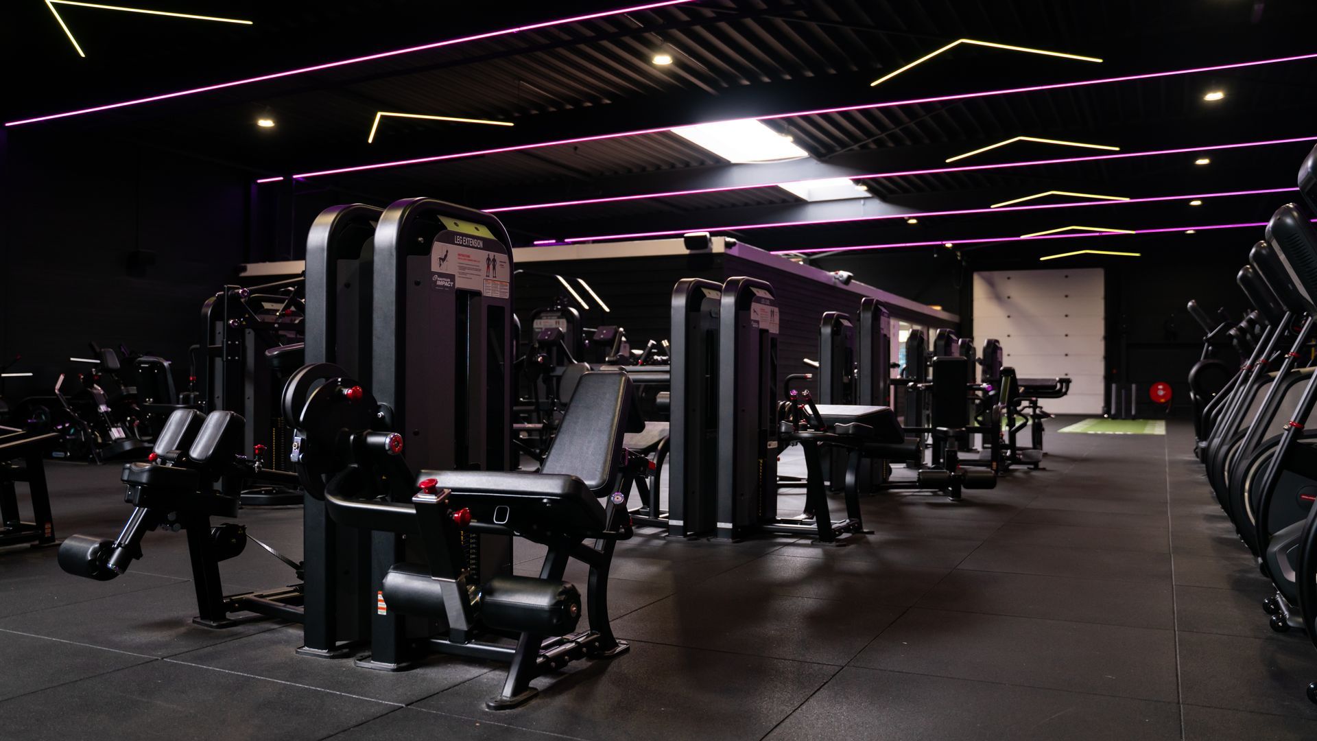 Rijen zwarte halters met witte gewichtslabels in een sportschool.