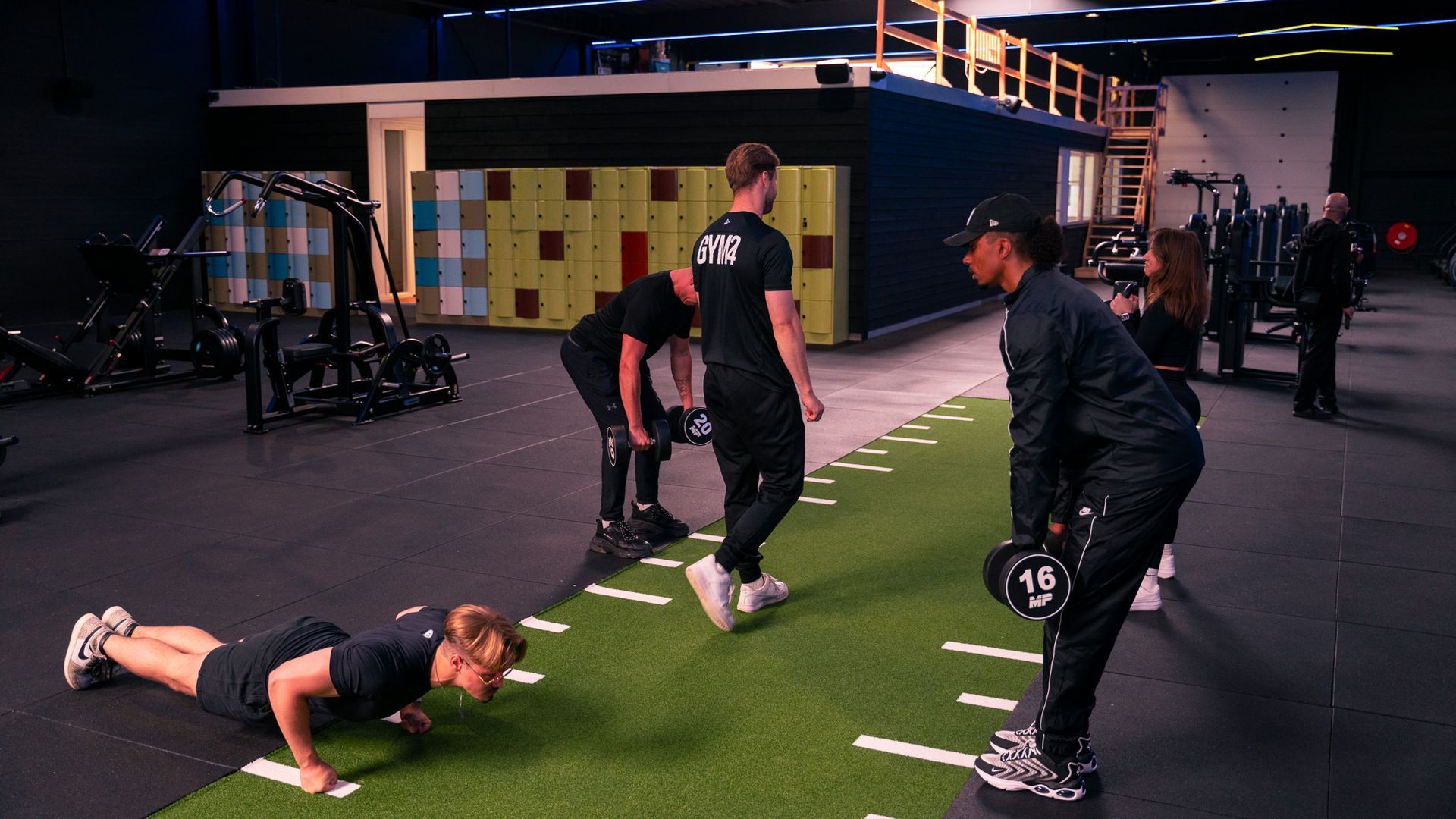 Mensen trainen in een sportschool: push-ups, dumbbell deadlifts en wandelen. Groen grasveld met witte lijnen.