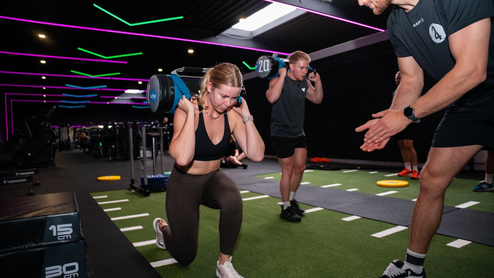 Mensen aan het sporten in een sportschool: de een doet push-ups, de ander houdt halters vast, en weer anderen kijken toe.