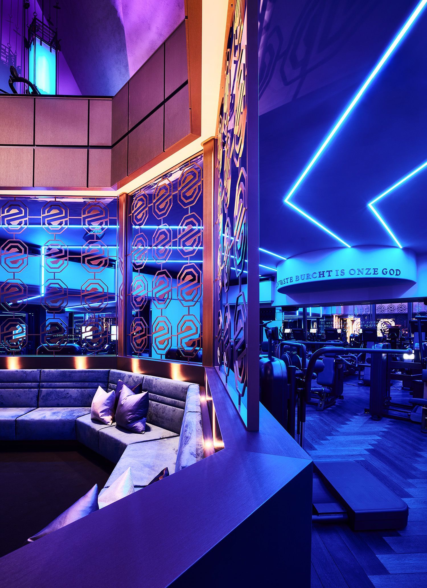 Interieur van een lounge met levendige blauwe en paarse neonlichten, modern design, zichtbare zithoeken.