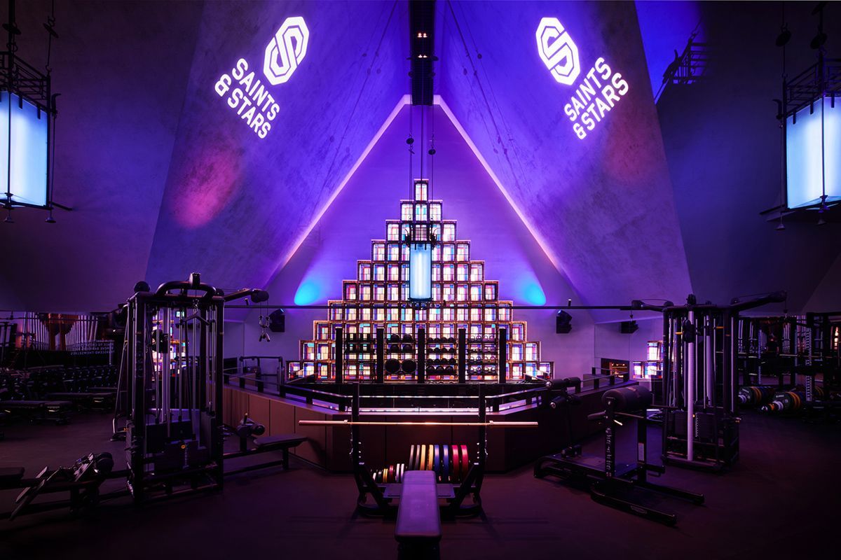 Interieur van de sportschool met een piramidevormige structuur, paarse verlichting en apparatuur. 