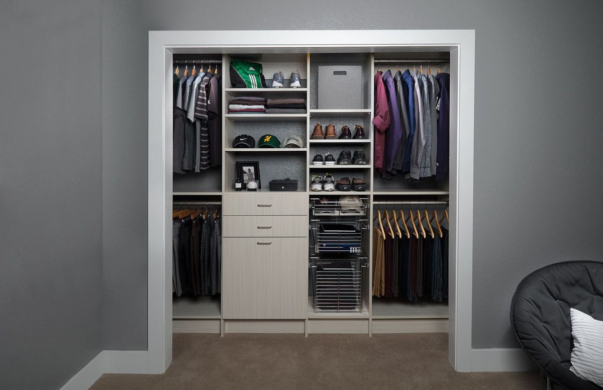 A reach-in closet with lots of clothes and shoes in it.