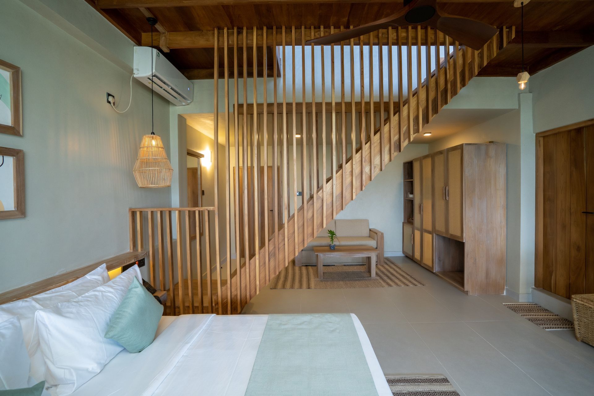 Bedroom with wooden staircase, light green walls, and natural wood accents.
