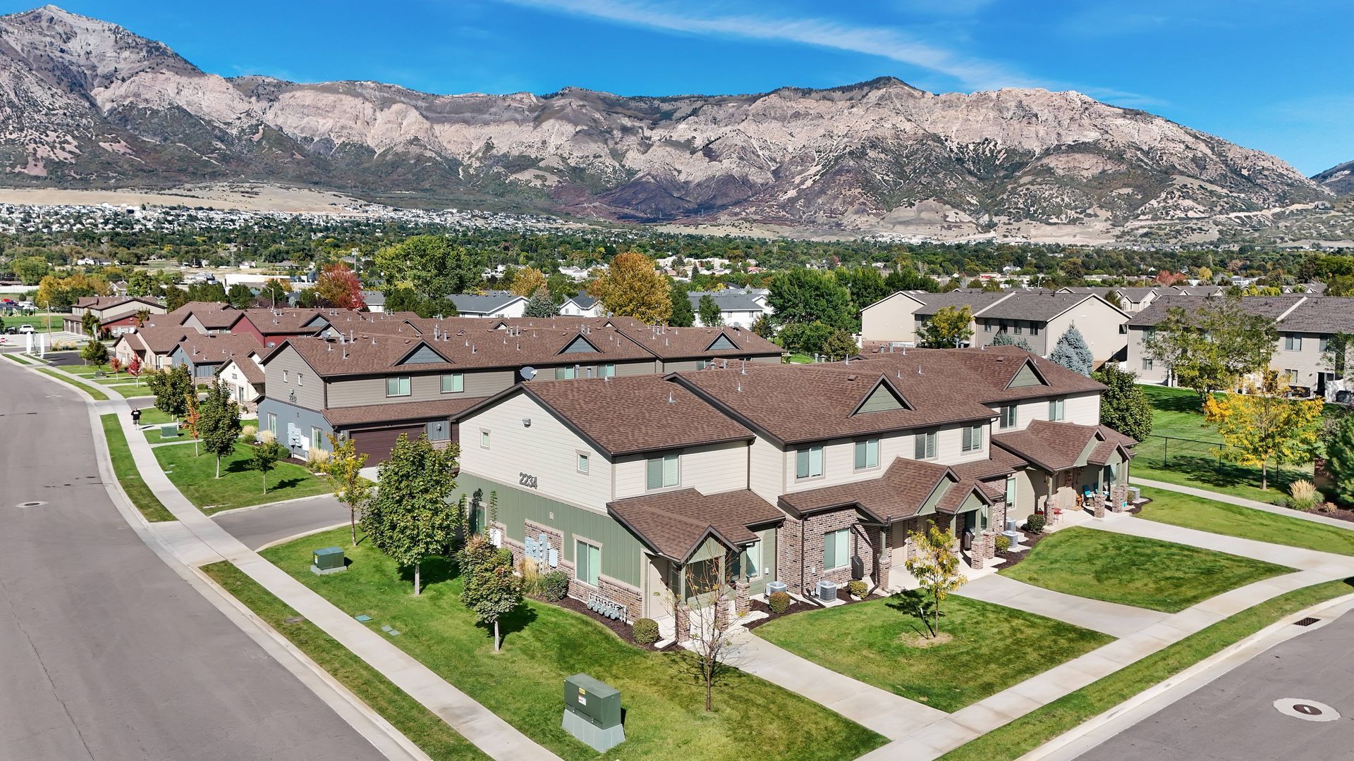 Townhomes in a suburban neighborhood with mountains in the background under a blue sky.