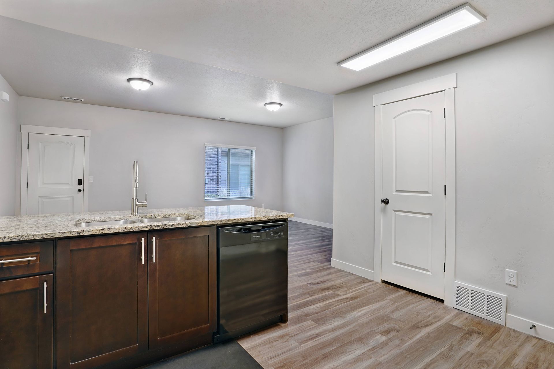 Kitchen with brown cabinets, granite countertop, stainless steel appliances, and wood-look flooring.