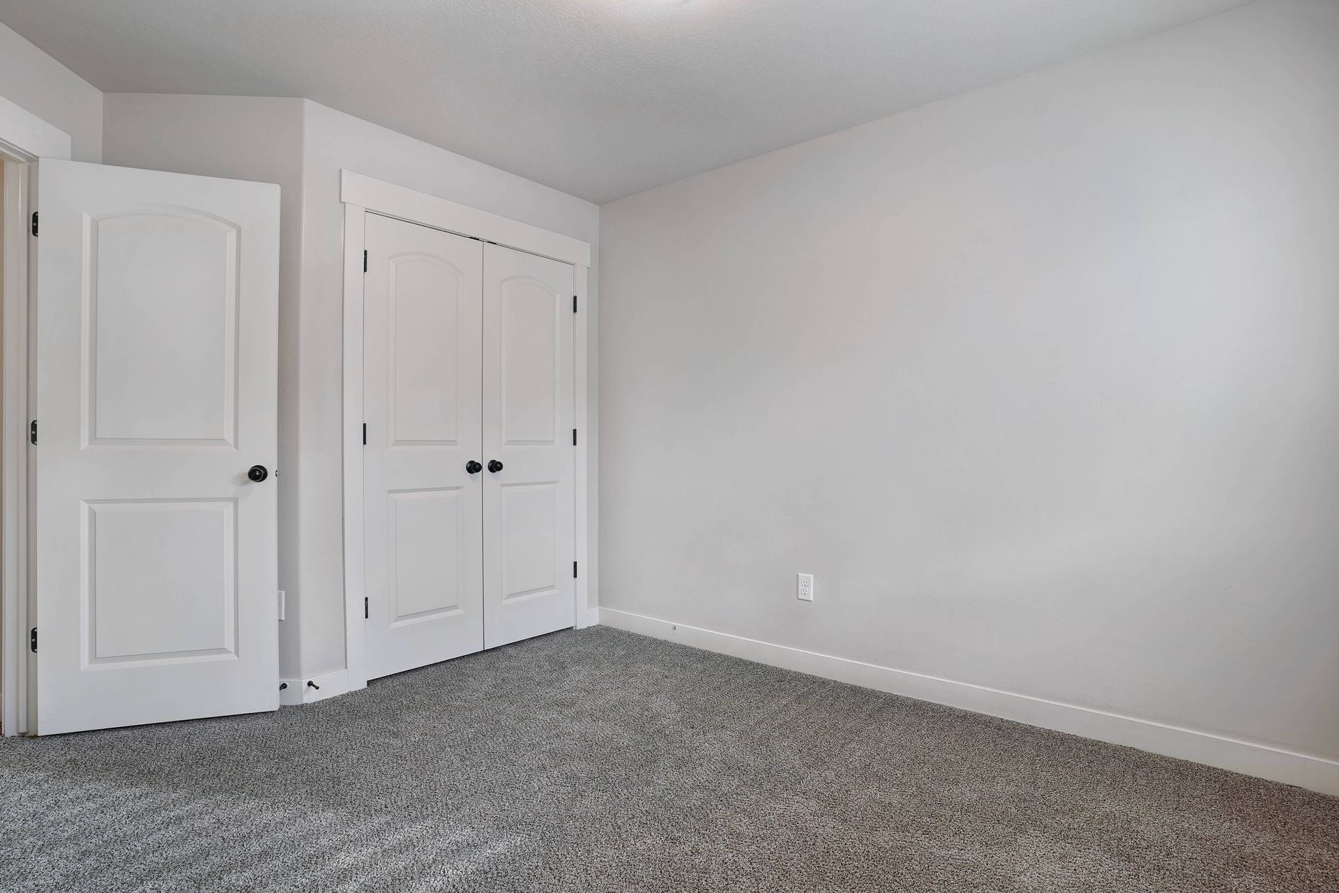 Empty room with beige carpet, white walls, and a window with blinds.