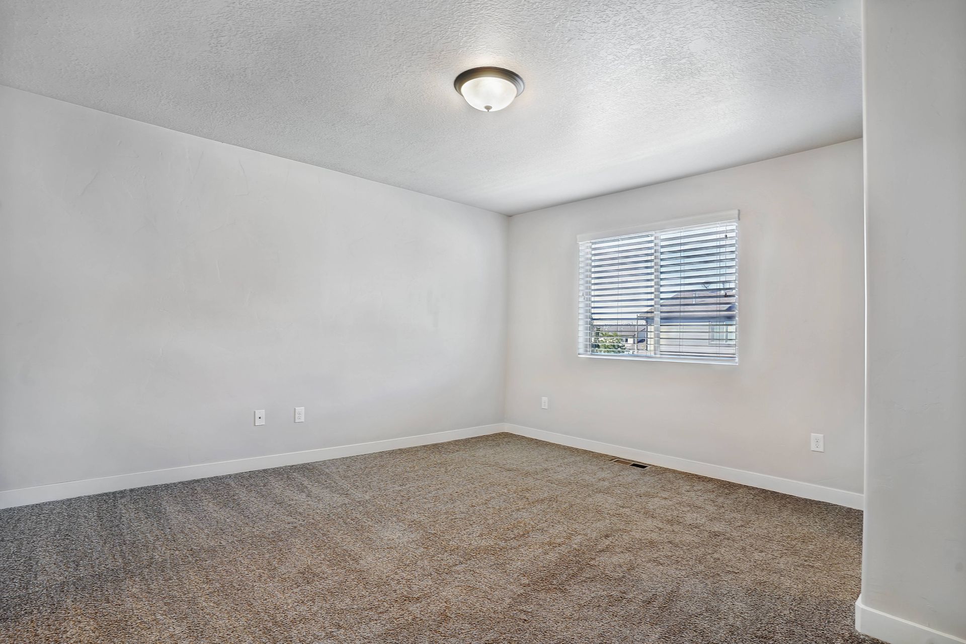 Empty room with beige carpet, white walls, and a small window with blinds.