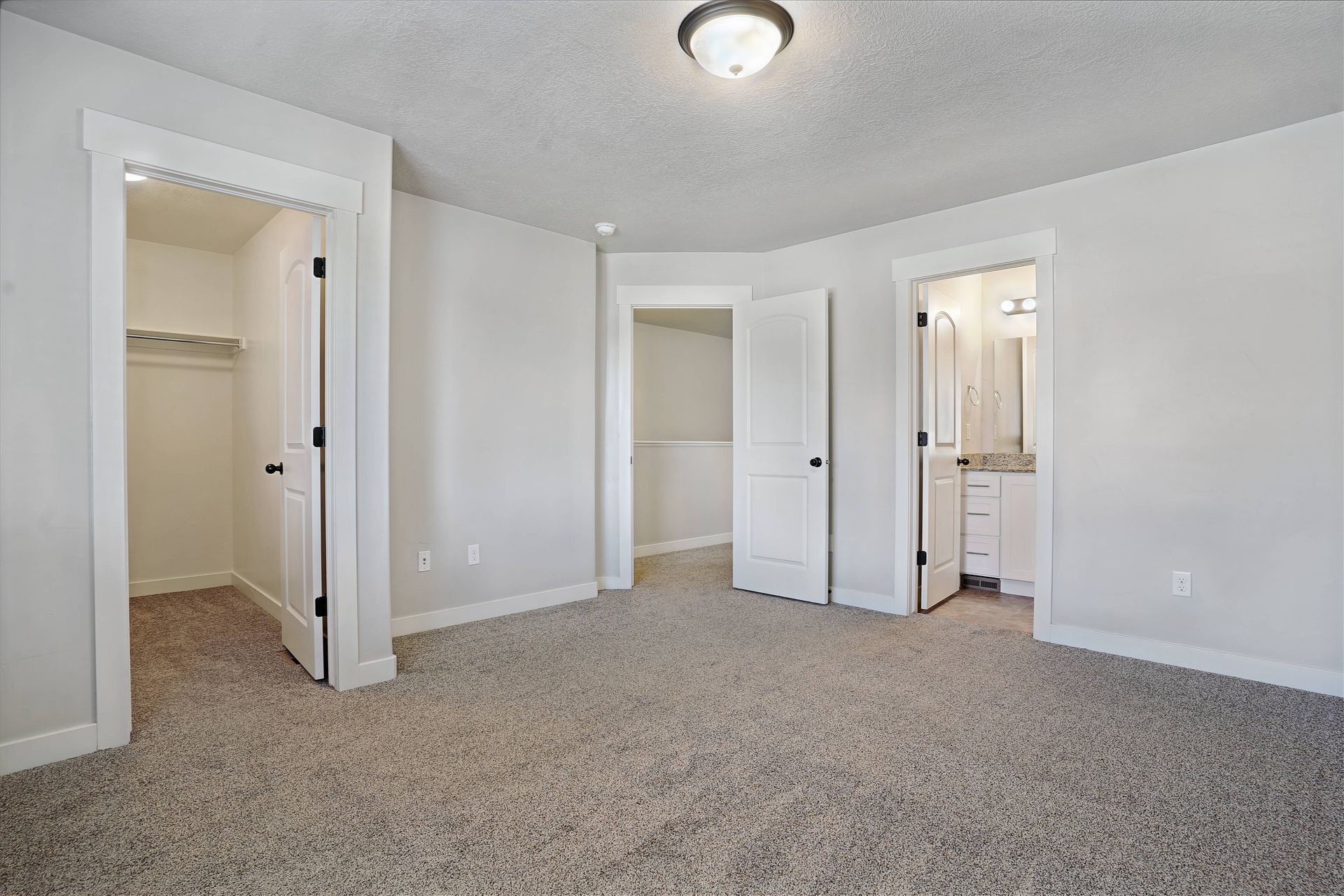 Bedroom with light carpet, closets, and a bathroom doorway.
