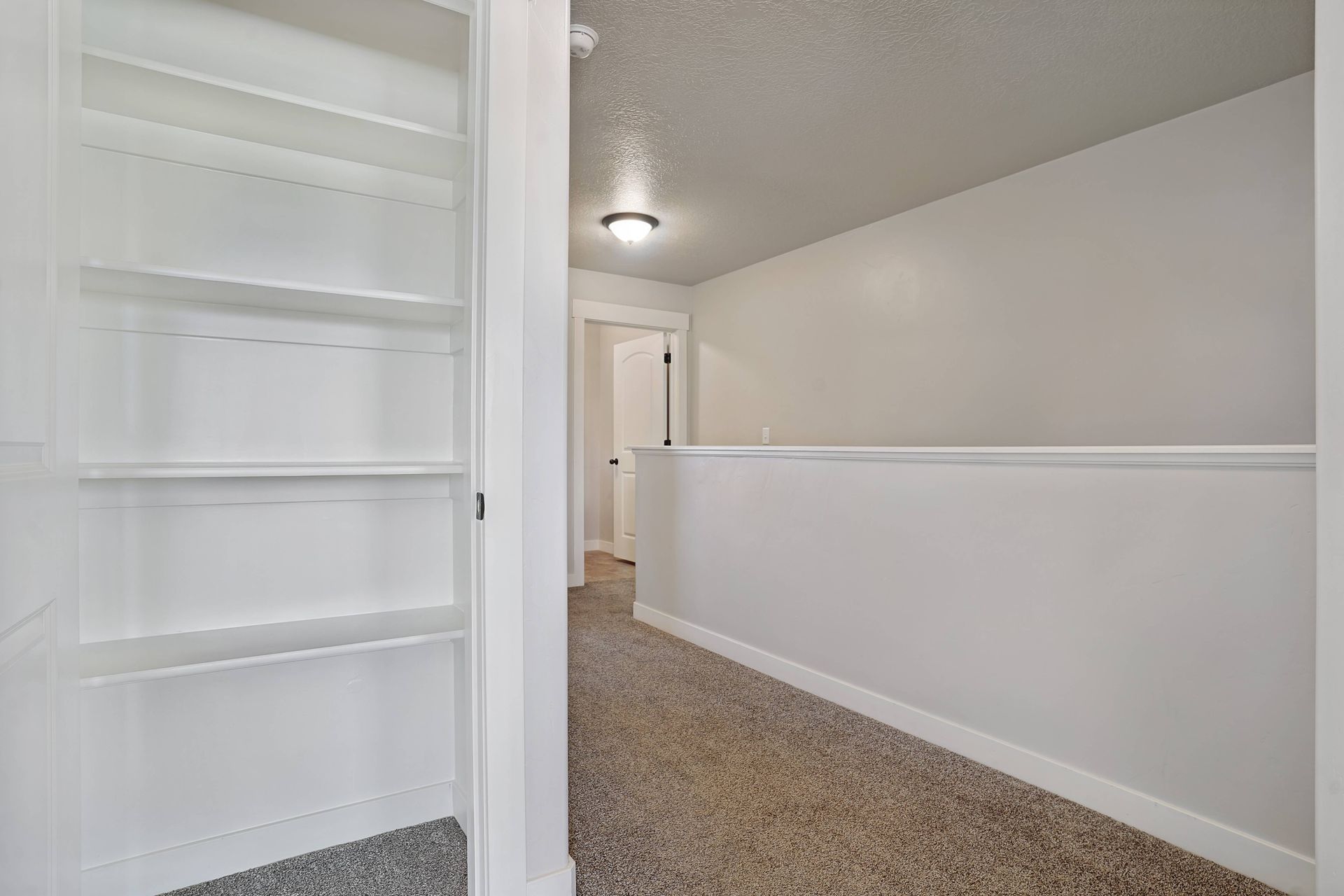 Hallway with gray carpet, white walls, and two doors.