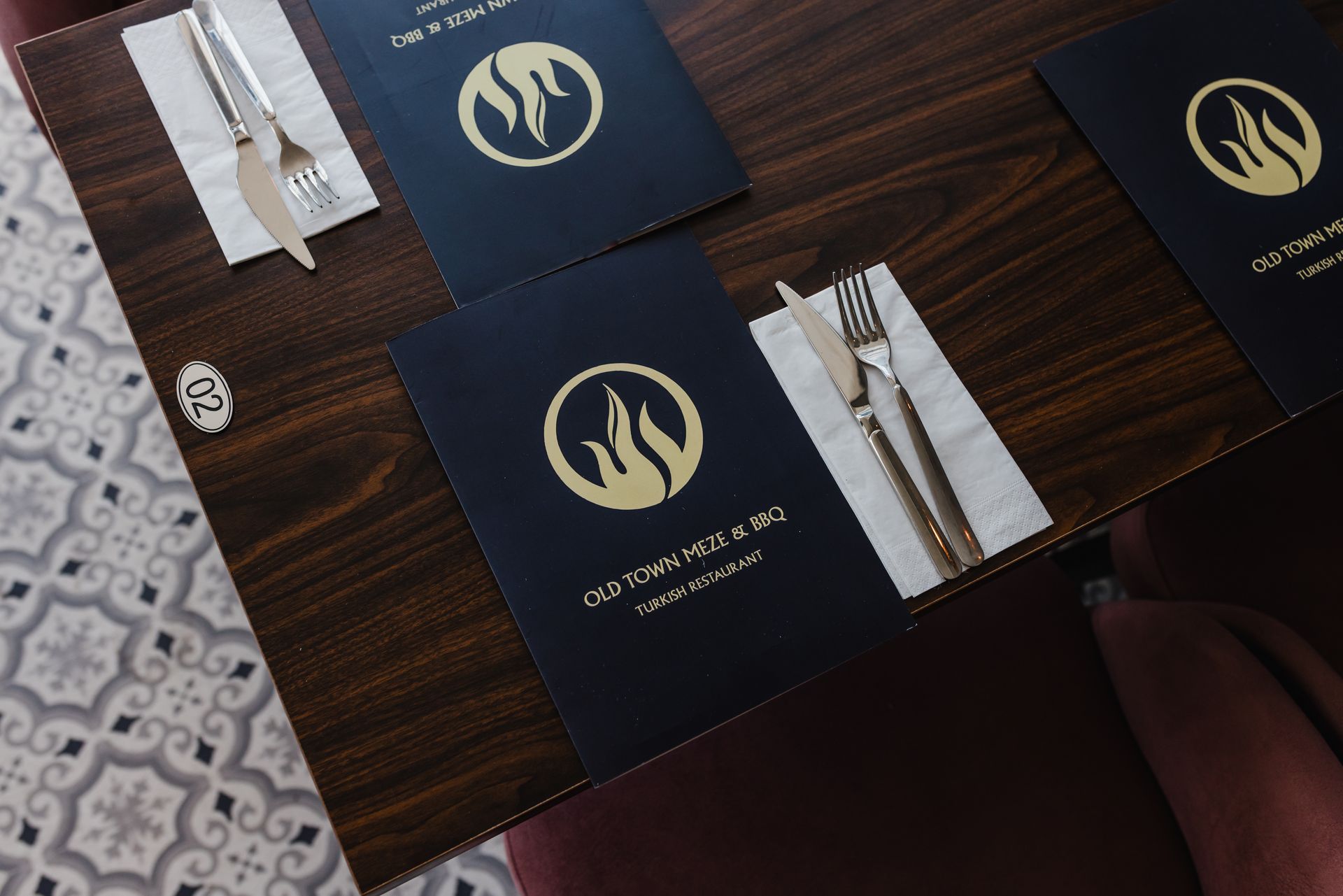 A wooden table with placemats and silverware for a restaurant