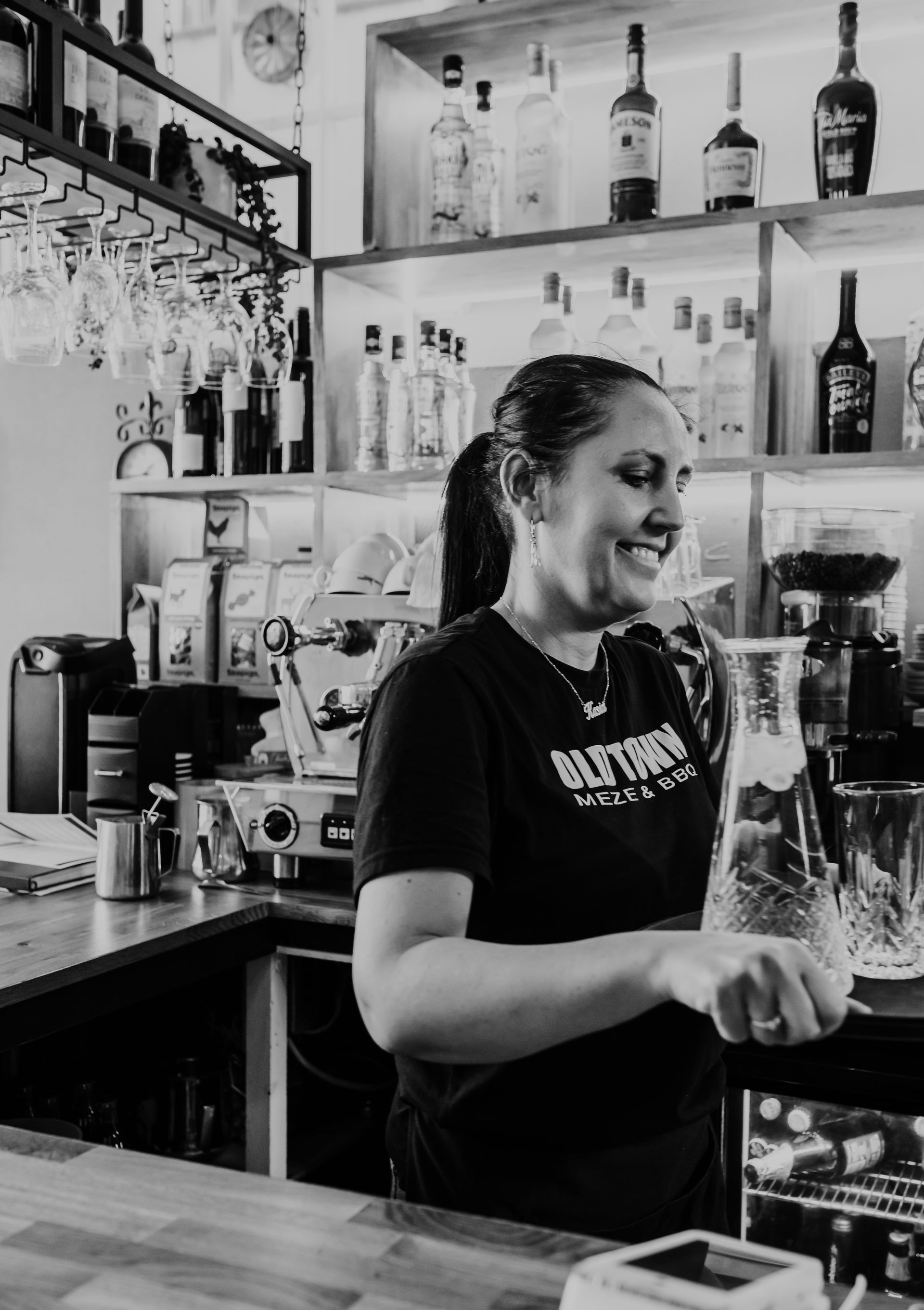 A woman is standing behind a bar making a drink.