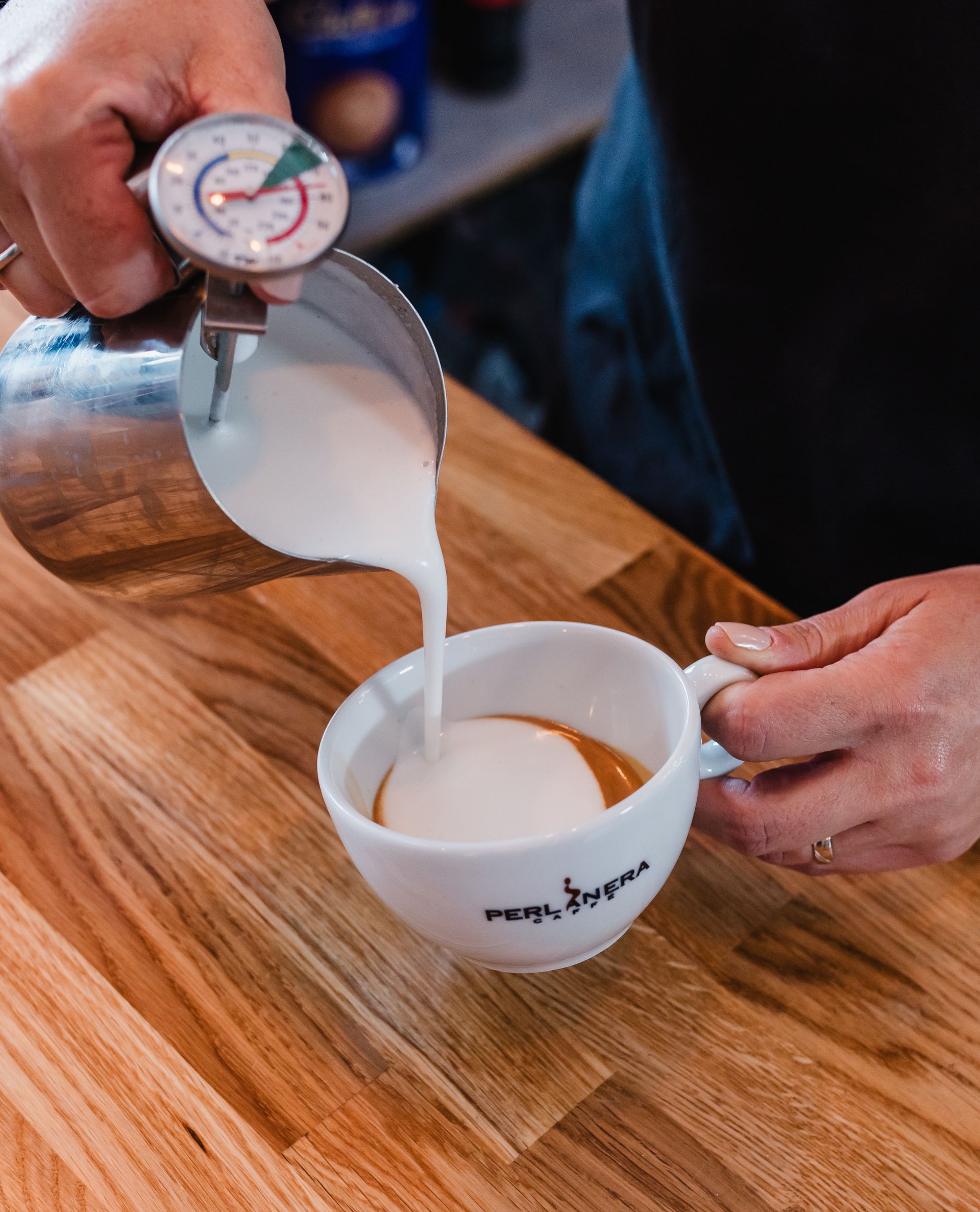 A person is pouring milk into a cup of coffee