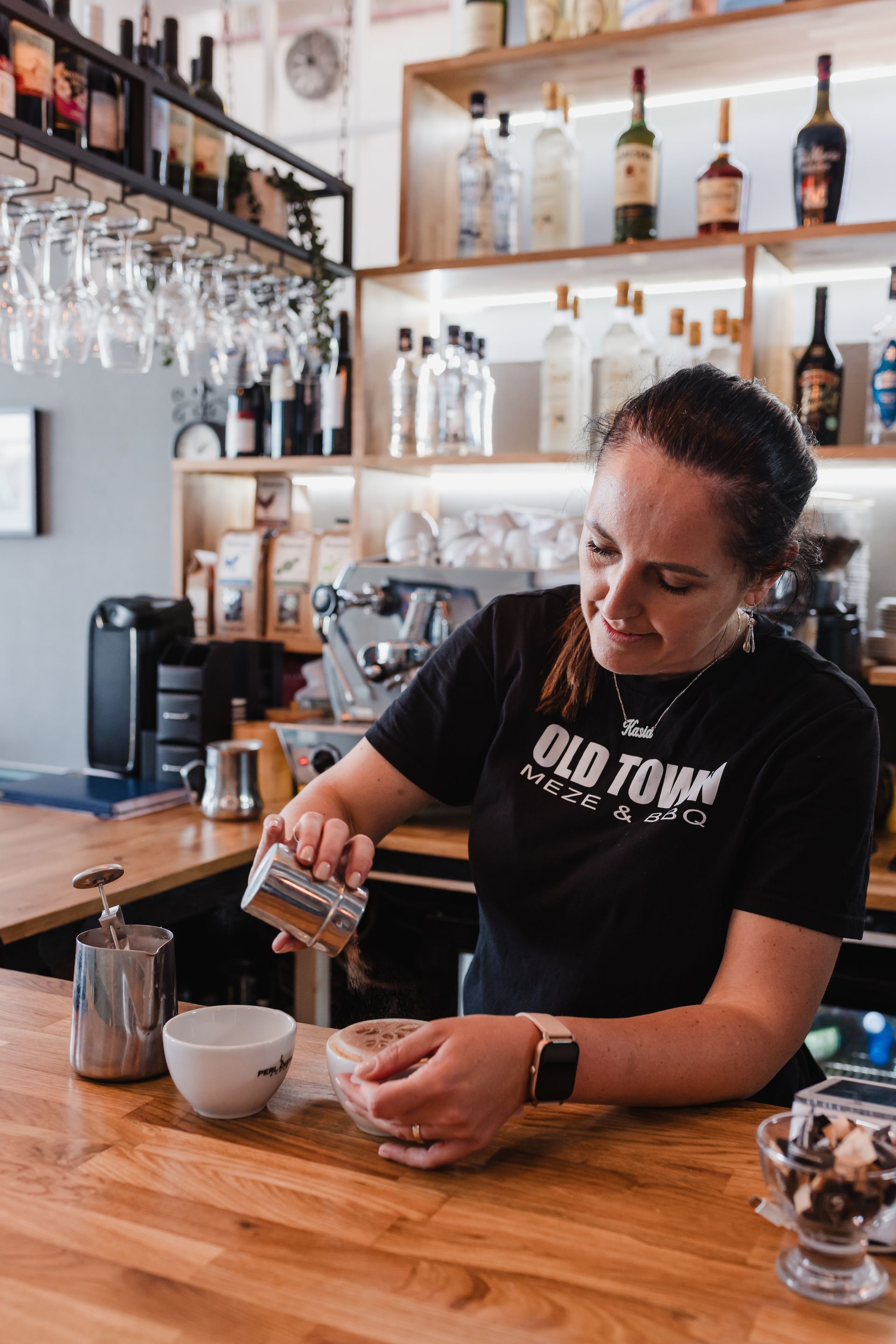 A woman wearing an old town shirt is preparing a drink
