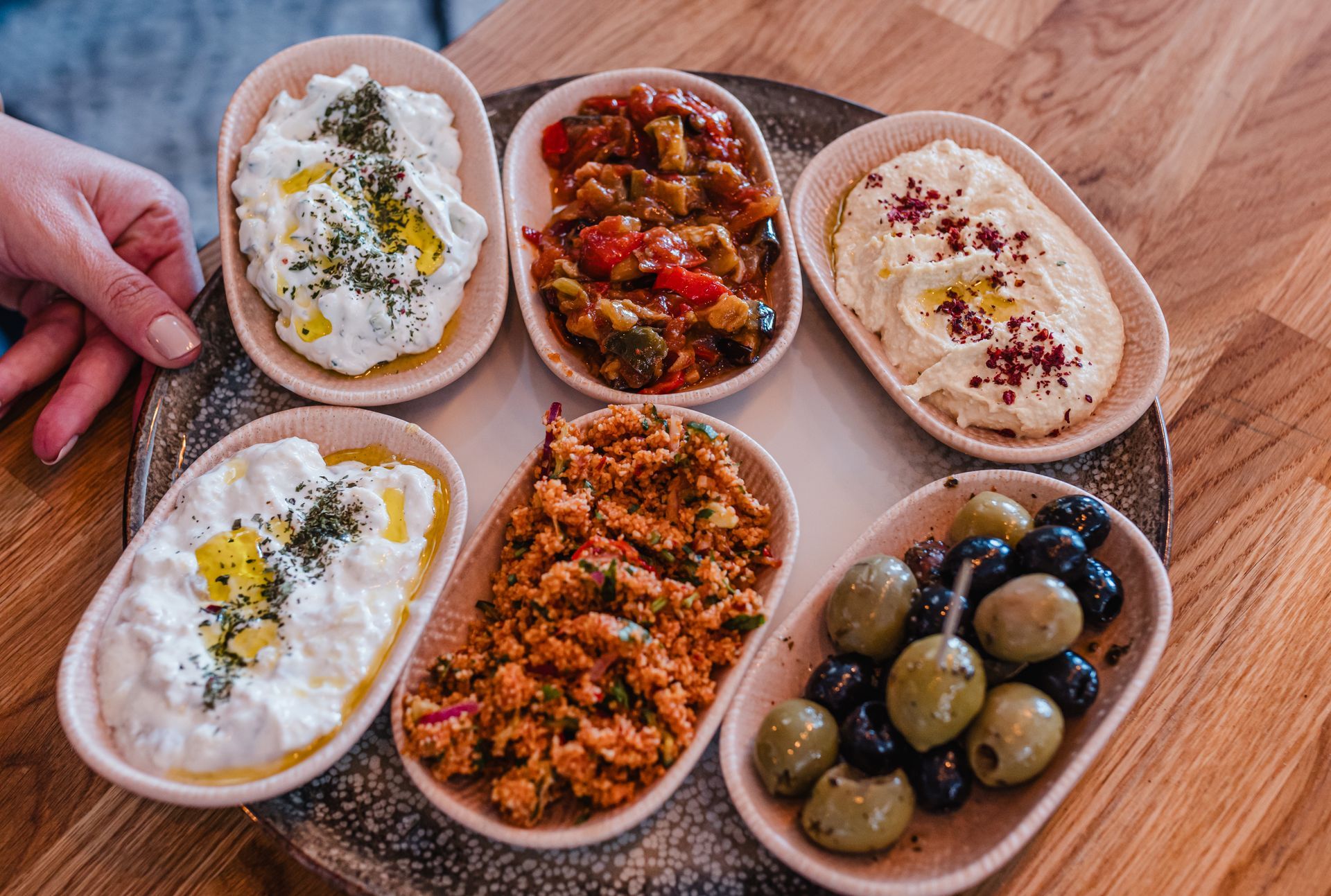A person is holding a plate of food on a wooden table.