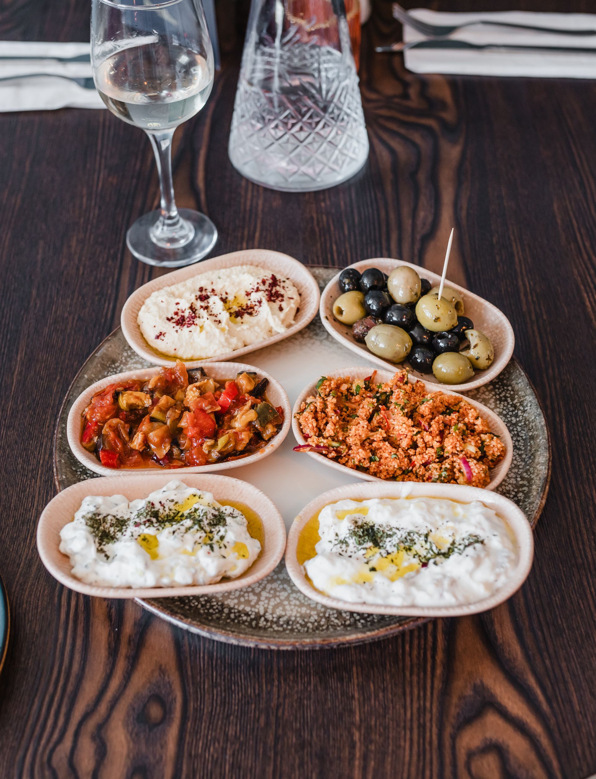 A plate of food on a wooden table next to a glass of wine