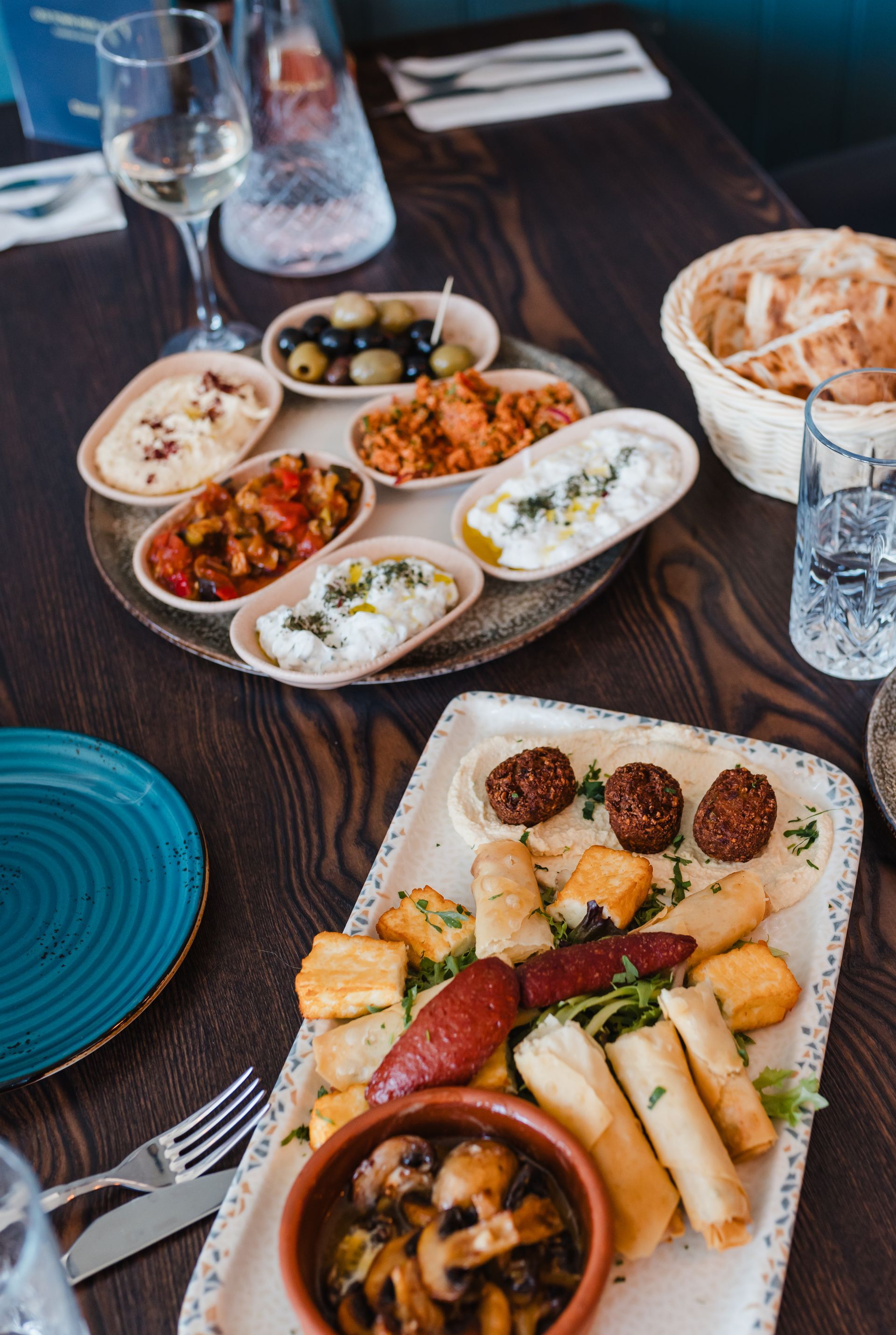 A table topped with plates of food and a glass of wine
