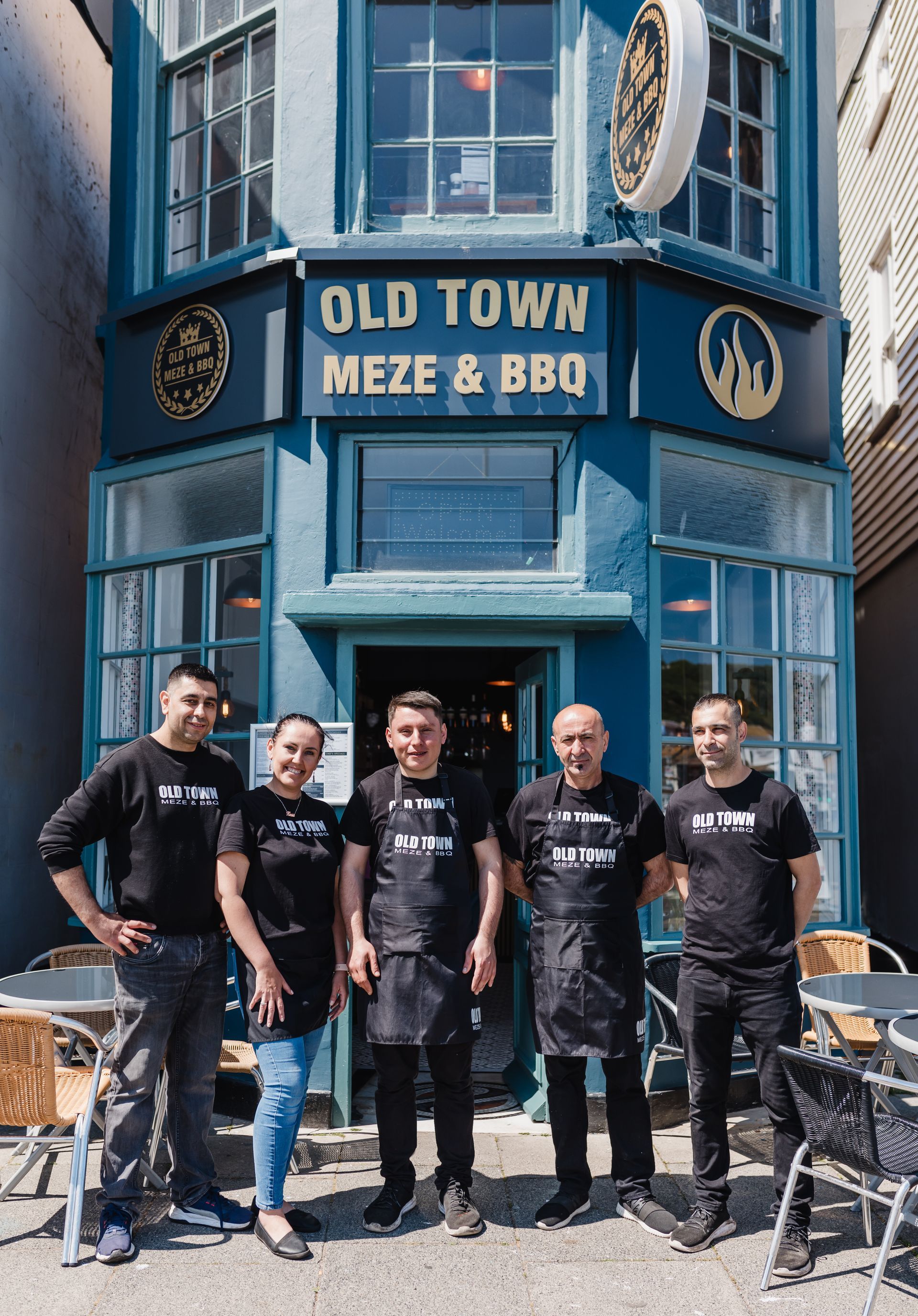 A group of men standing in front of an old town meze & bbq restaurant