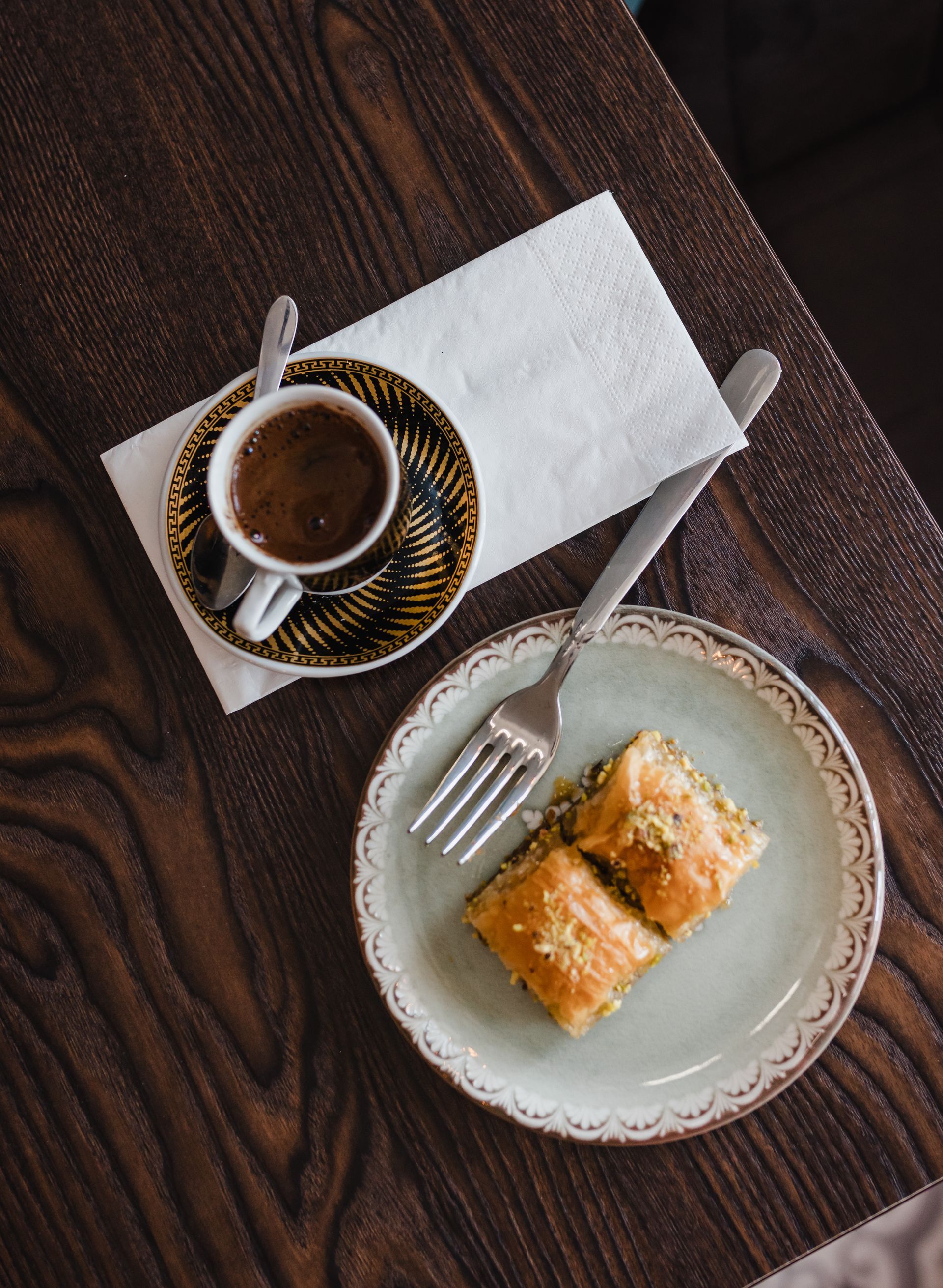 A plate of baklava next to a cup of coffee