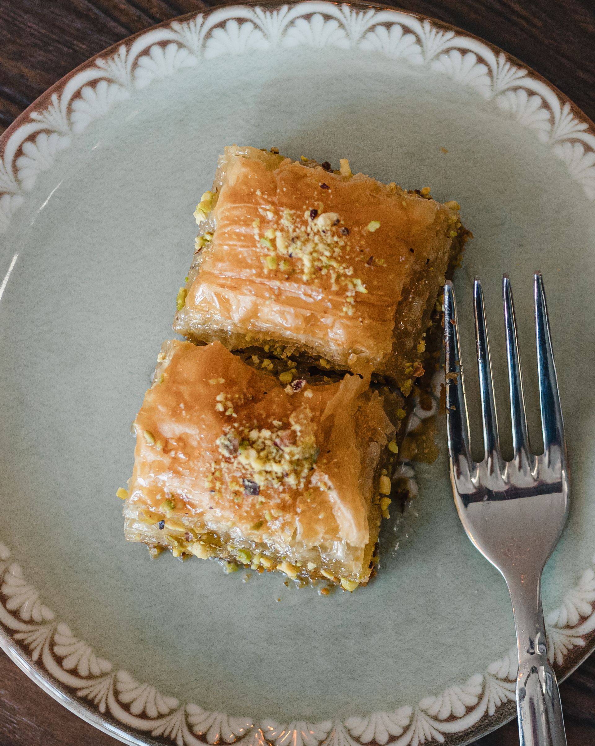 Two pieces of baklava on a plate with a fork