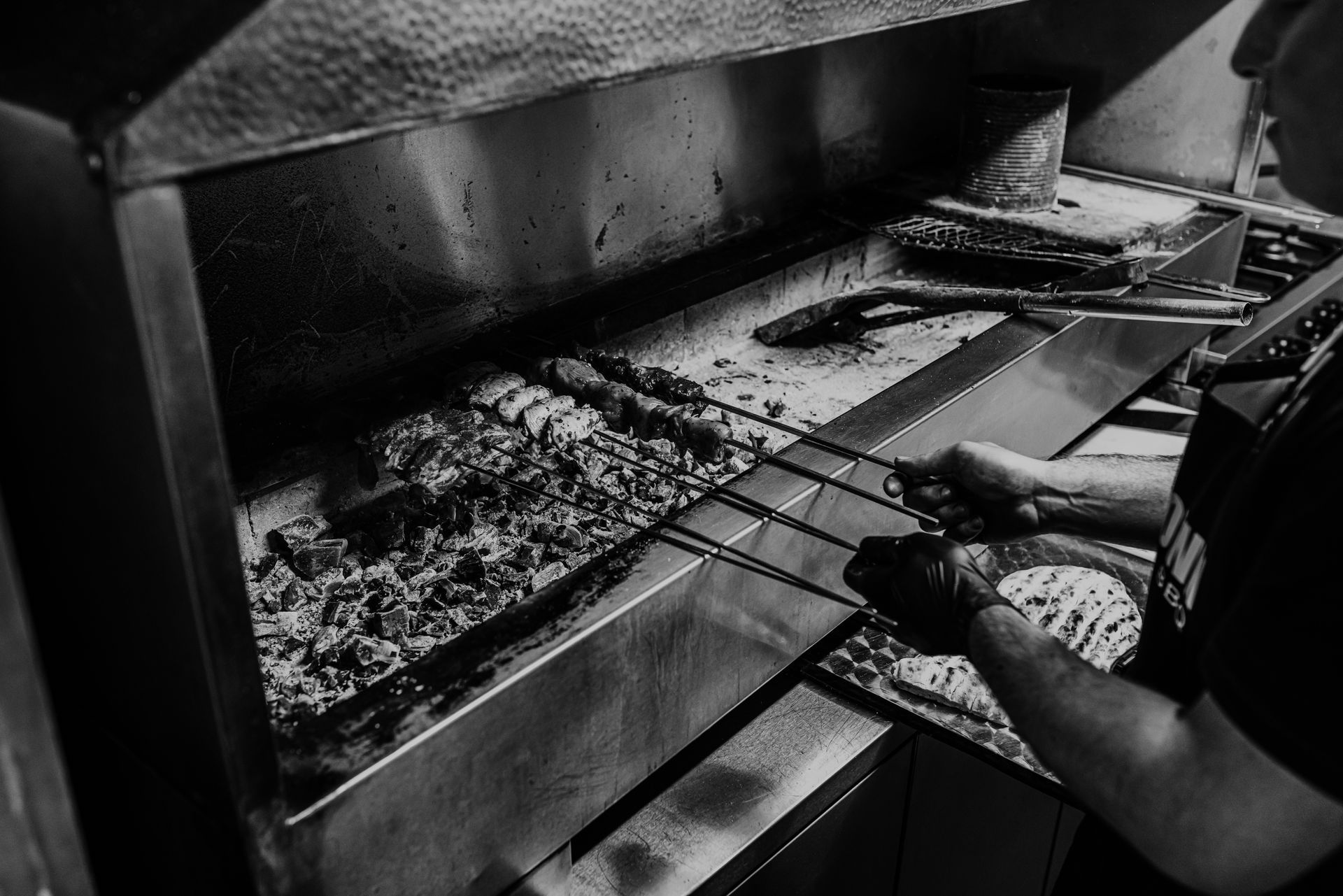 A man is cooking food on a grill in a black and white photo.