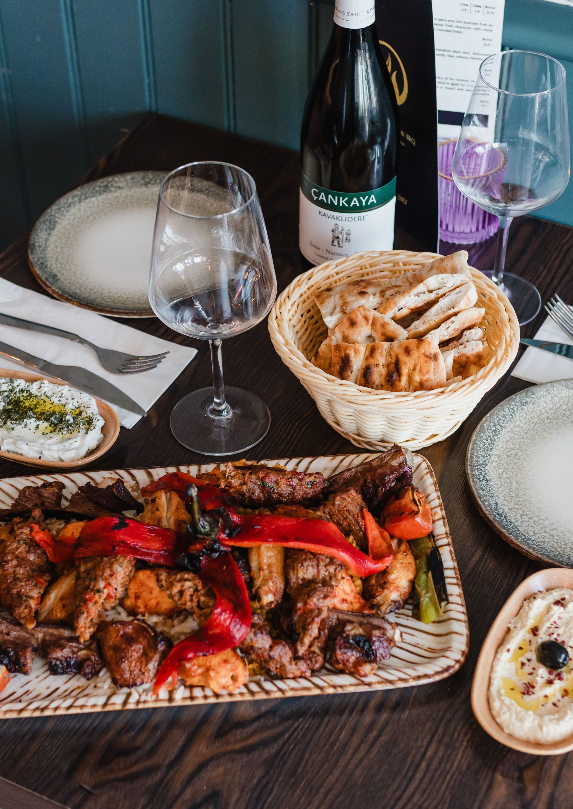 A bottle of wine sits on a table next to a plate of food