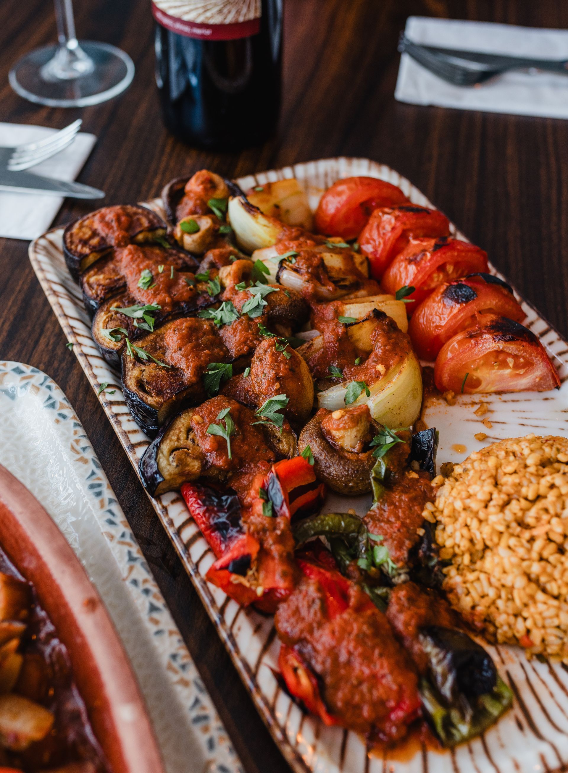 A plate of food on a table with a bottle of wine in the background