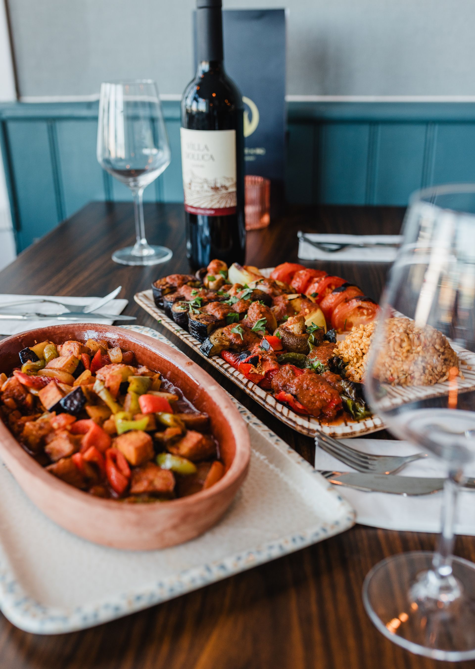 Two plates of food and a bottle of wine on a table