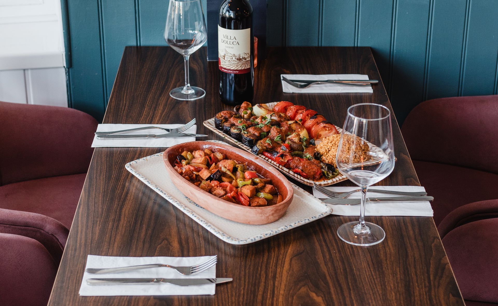 A table with two plates of food and a bottle of wine