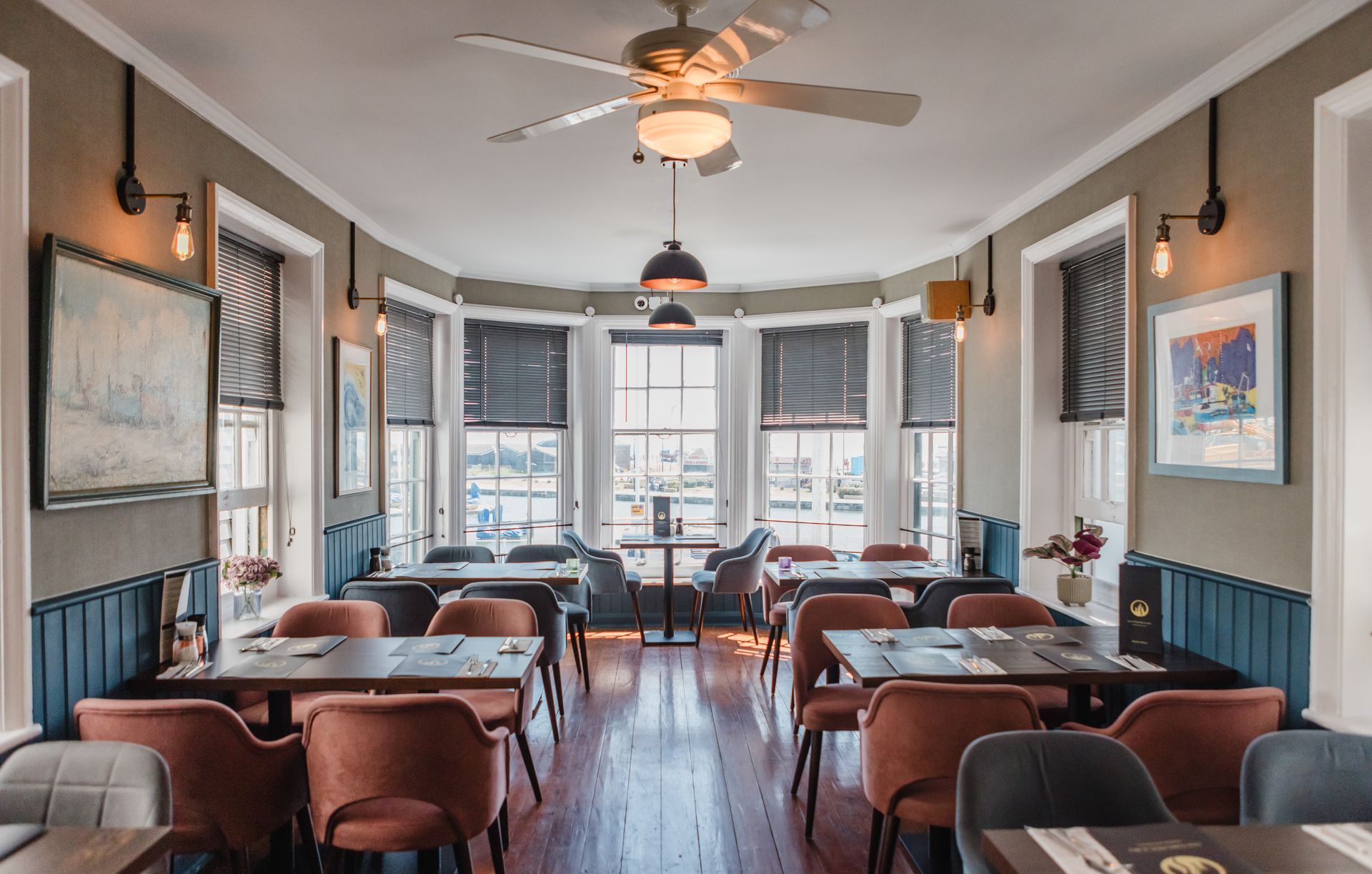 A restaurant with tables and chairs and a ceiling fan