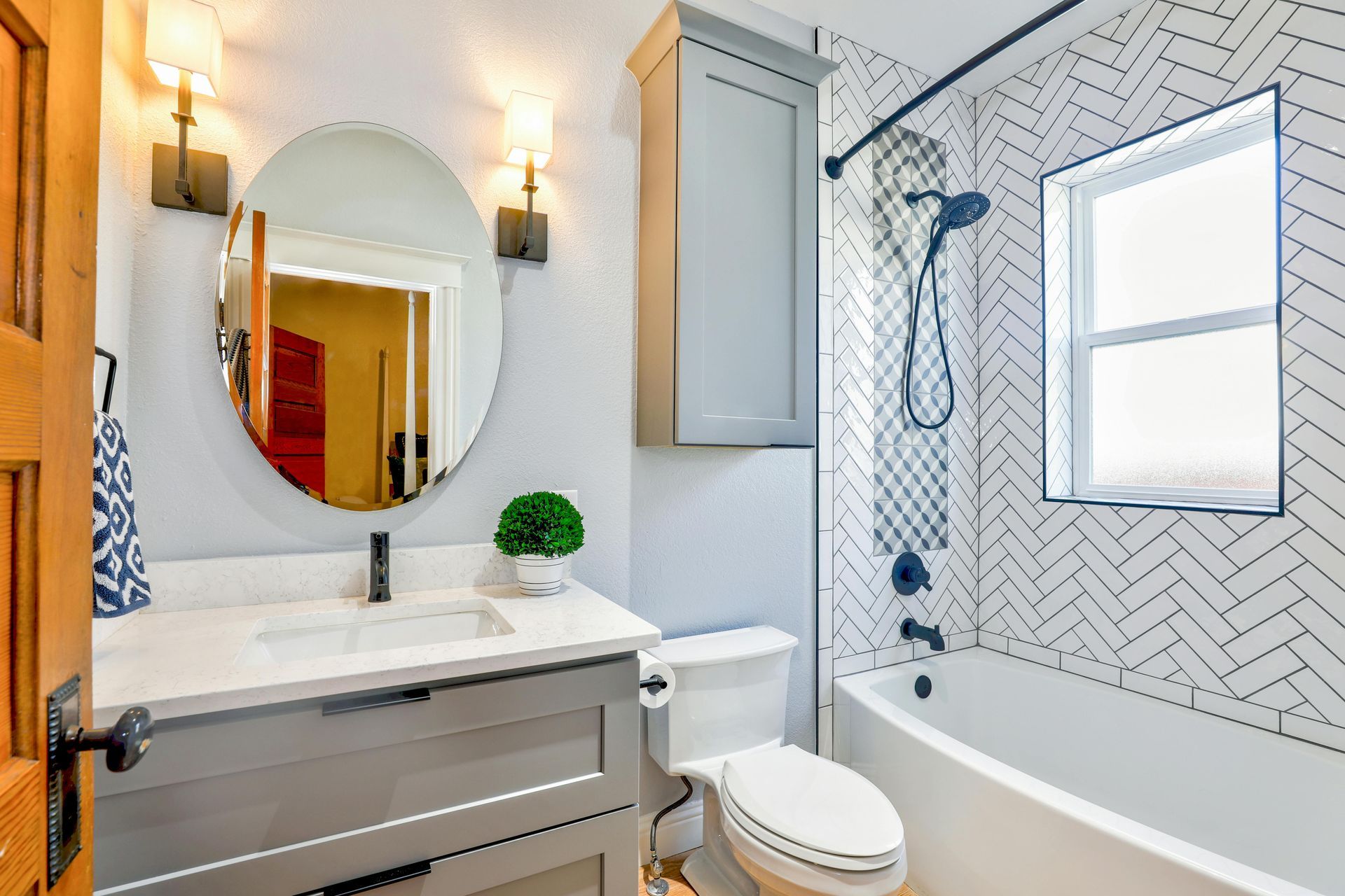 Bathroom with a gray vanity, white toilet, and herringbone tile in a modern style.