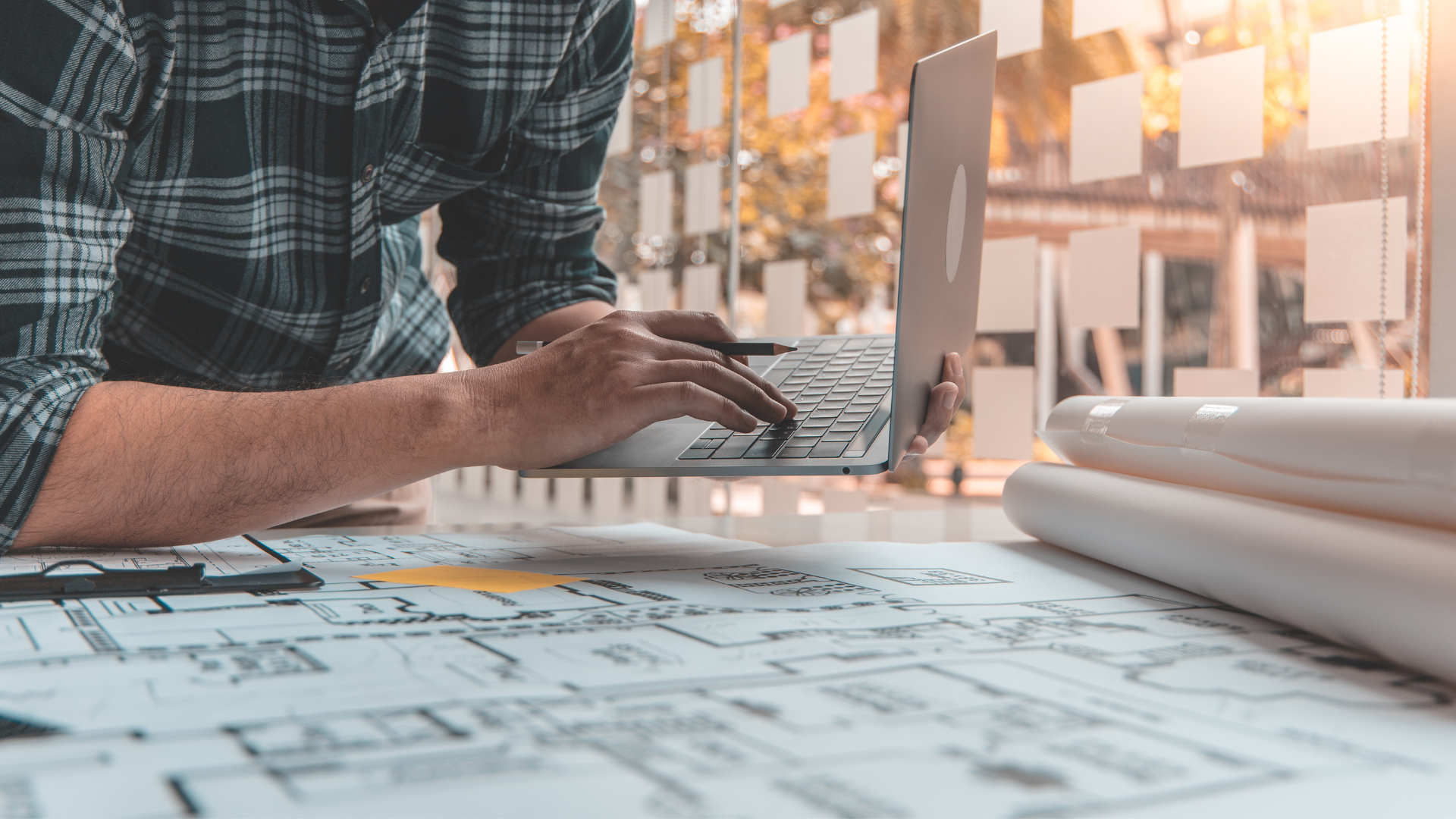 A man is typing on a laptop computer while sitting at a desk.