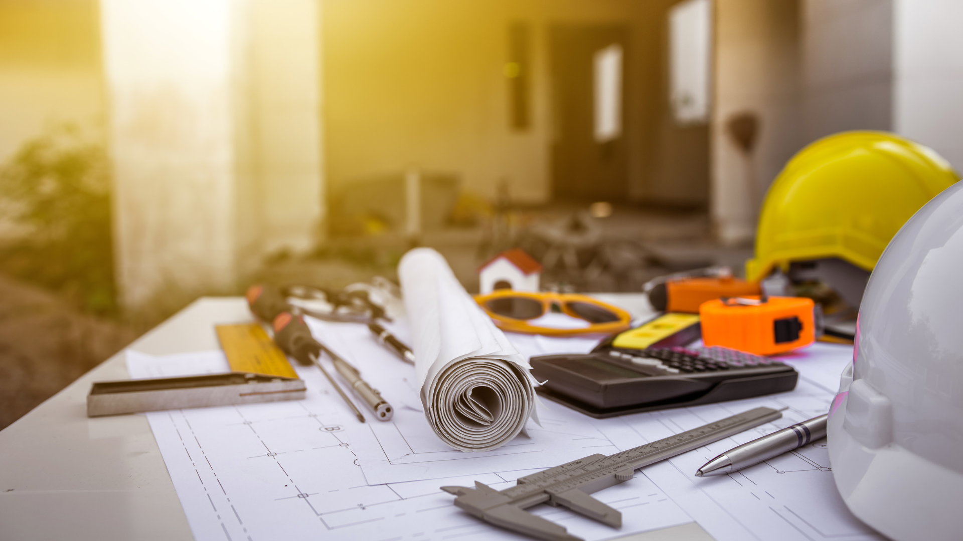 A hard hat is sitting on top of a table with construction tools.