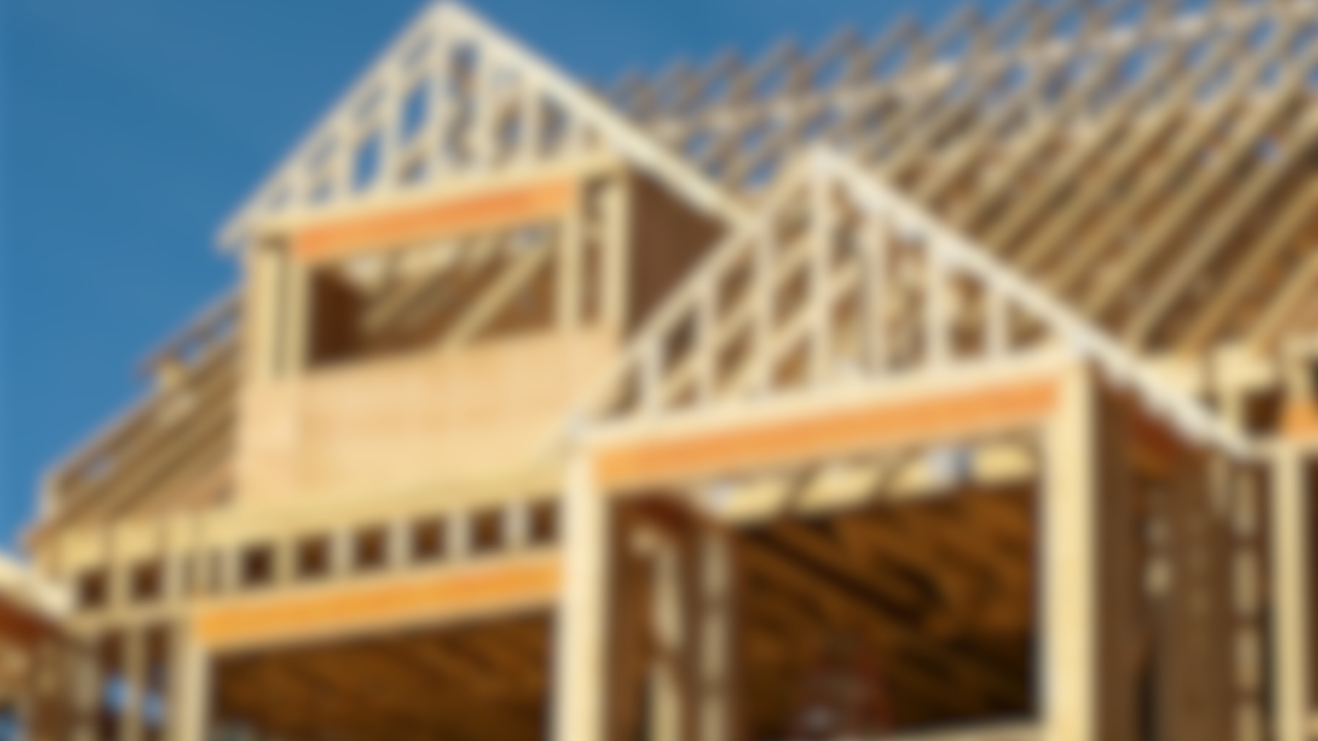 A large wooden house is being built with a blue sky in the background.