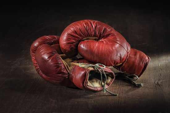 Old red boxing gloves on wooden background