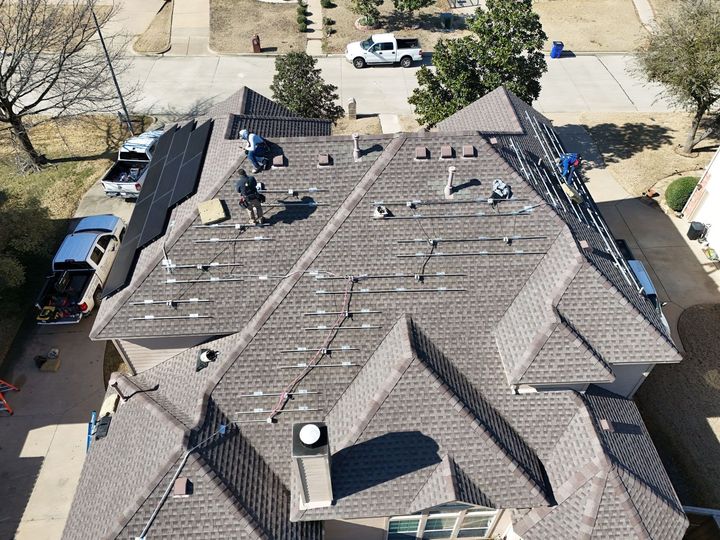 Roofers installing solar panels on a residential roof; sunny day.