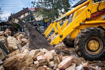 Yellow excavator pushing rubble at a demolition site