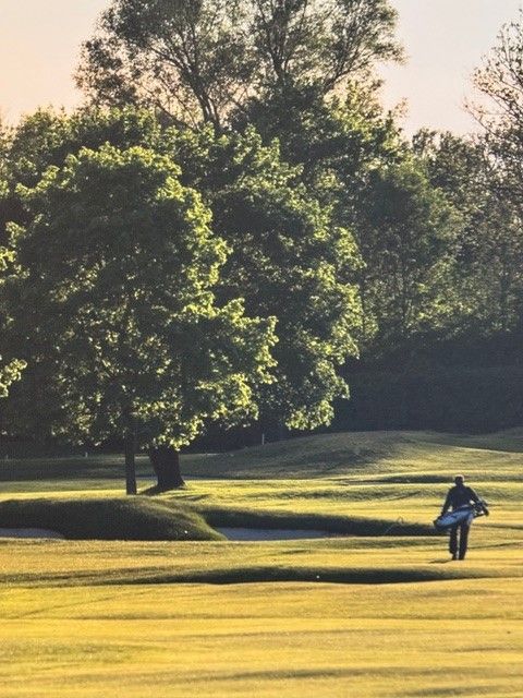 Ein Mann trägt eine Golftasche auf einem Golfplatz
