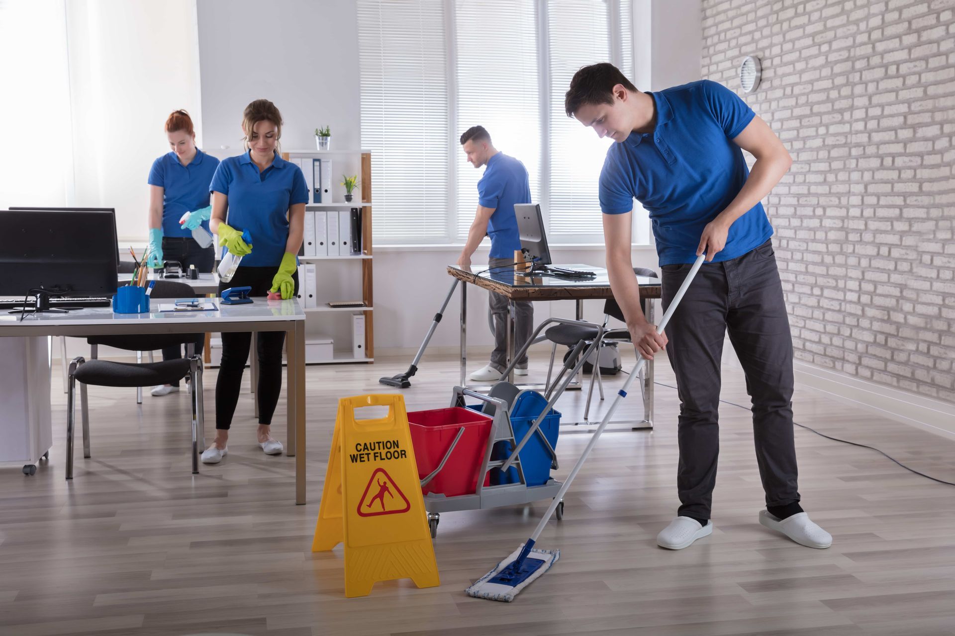 Group Of Janitors Cleaning The Modern Office