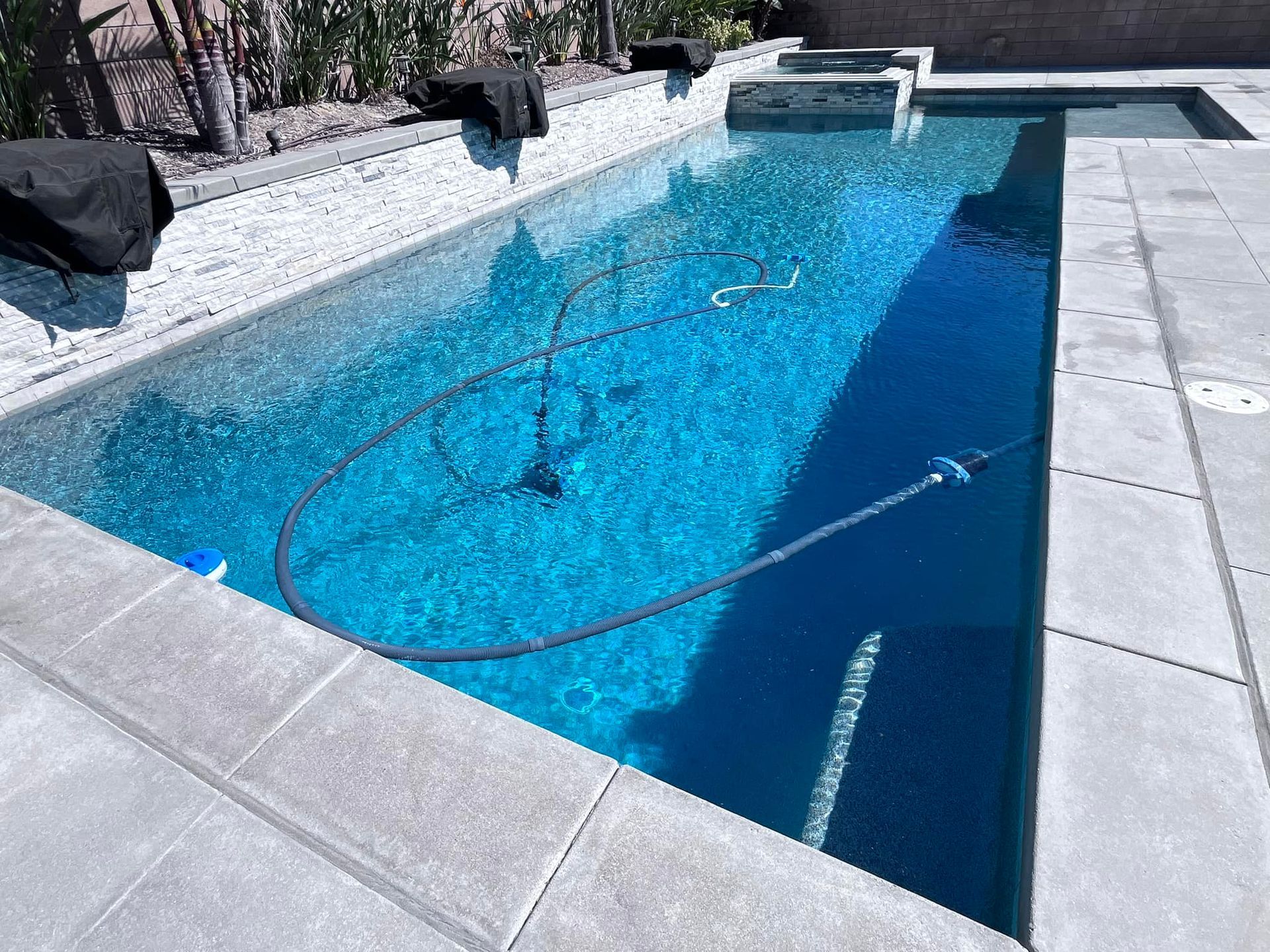 Woman in straw hat smiles, holding wine glass near a lake.