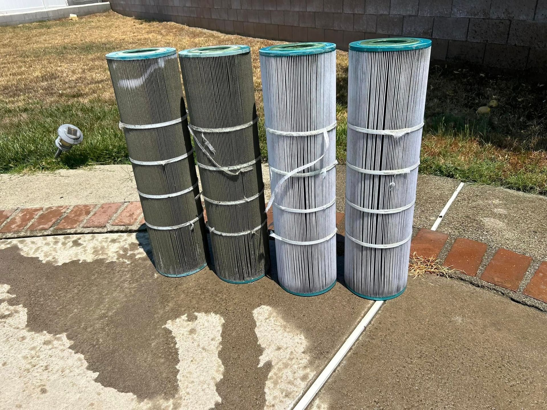 Woman in straw hat smiles, holding wine glass near a lake.