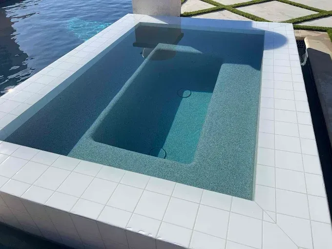 Rectangular plunge pool with white tiled border. The pool has blue-green tiled interior, with steps.