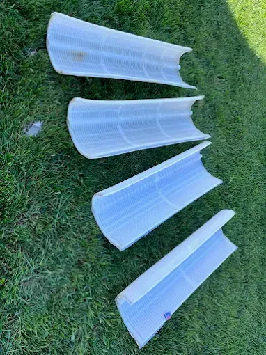 Four curved, translucent plastic light diffusers on green grass.