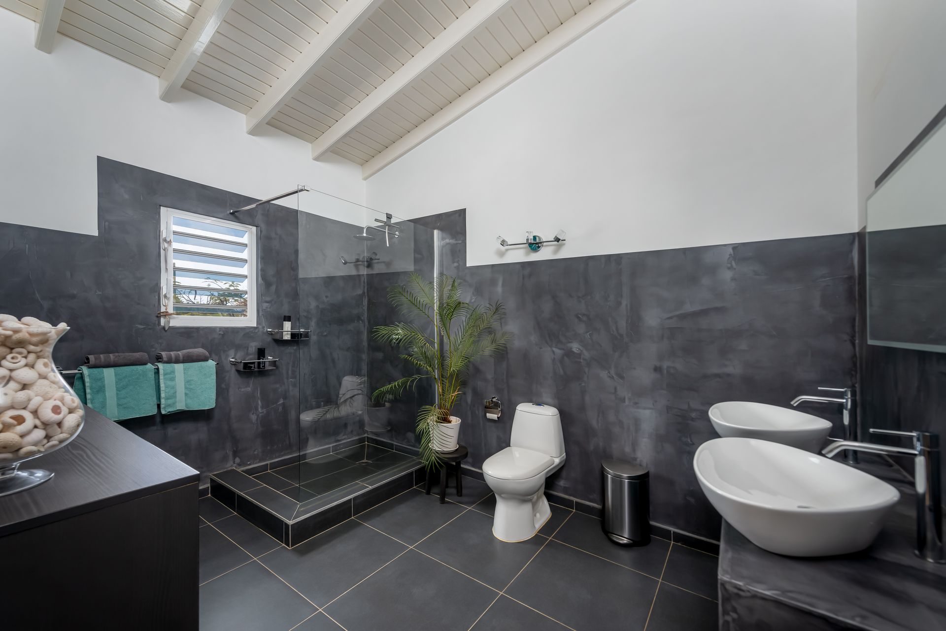 A bathroom with two sinks , a toilet and a walk in shower.