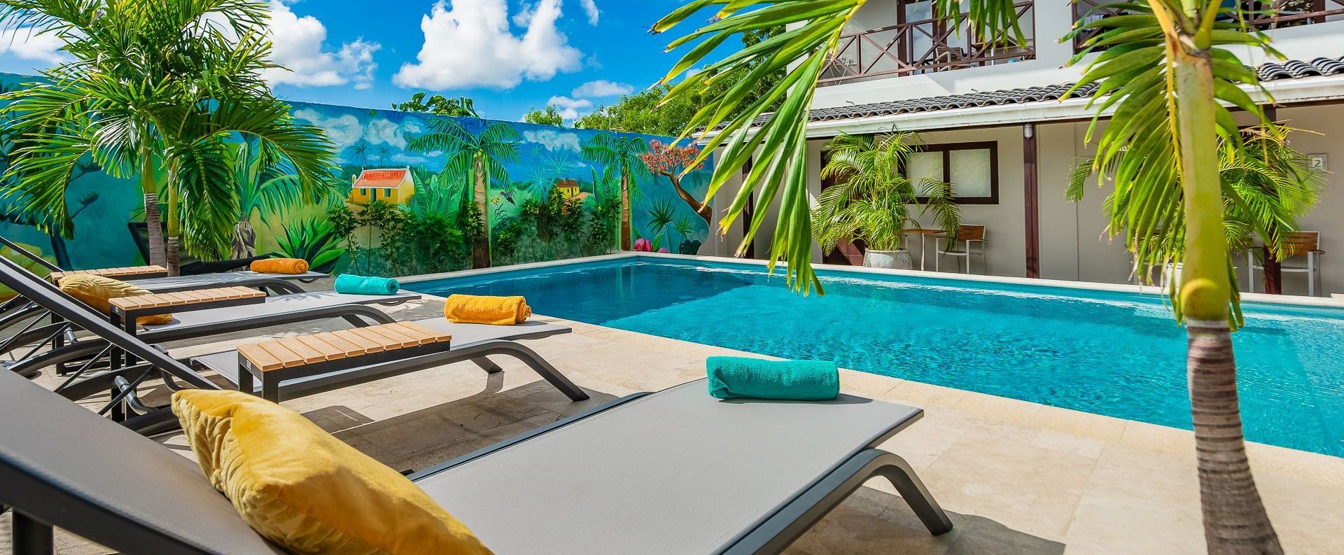 A large swimming pool surrounded by lawn chairs and palm trees.